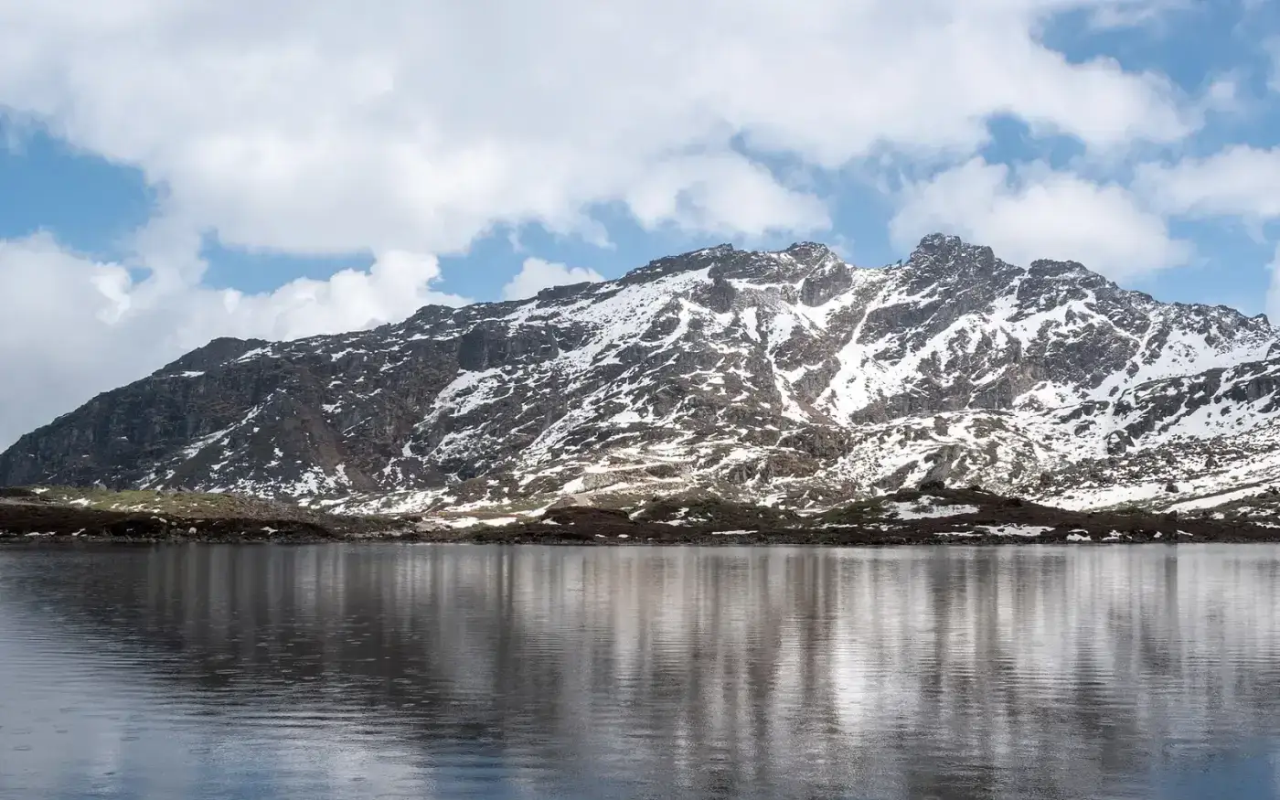 High-altitude lake below snowy peaks near Bum La